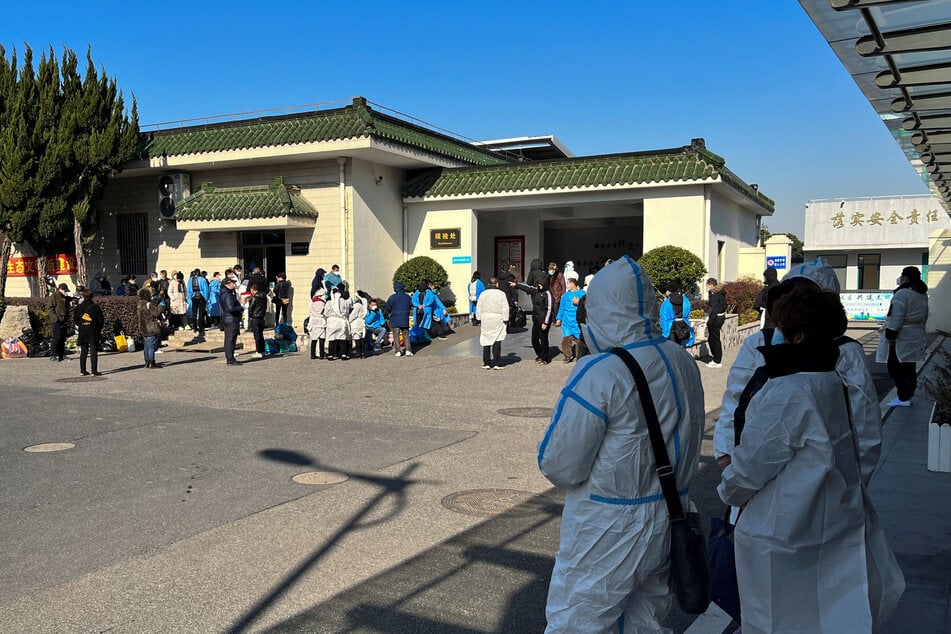 People wearing personal protective equipment (PPE) stand outside a funeral home in Shanghai.