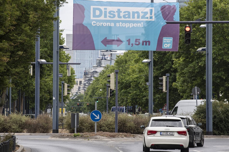"Distanz! Corona stoppen!" steht auf einem Banner, der über eine Haupteinfahrtstraße nach Offenbach gespannt ist.