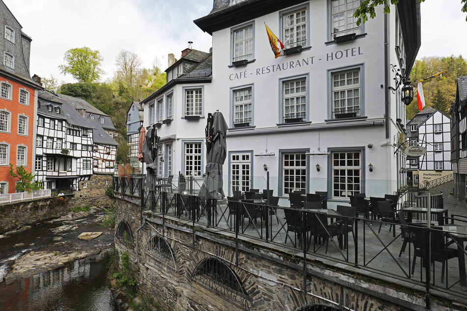 Tische und Stühle stehen in Monschau vor einem geschlossenen Hotel.