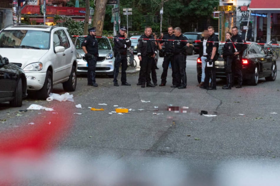 Polizeibeamte stehen vor dem abgesperrten Tatort.