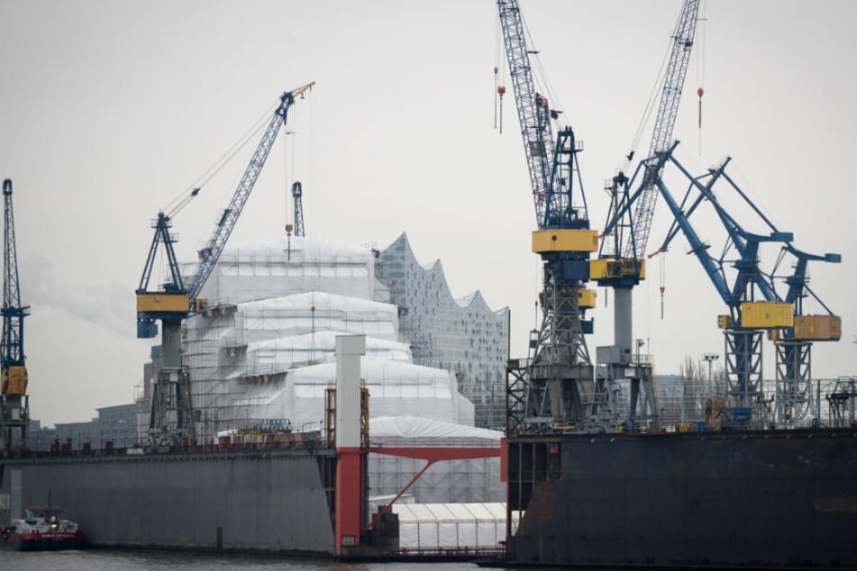 Diesen Anblick gibt es bald nicht mehr: Die Silhouette der Elbphilharmonie zeichnet sich hinter einem mit Planen geschützten Schiff im Schwimmdock 10 bei Blohm+Voss ab.