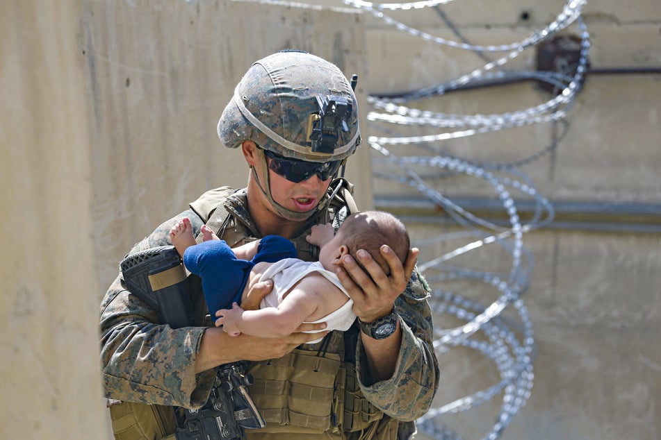 A US marine holding a baby as the evacuation operation continues.