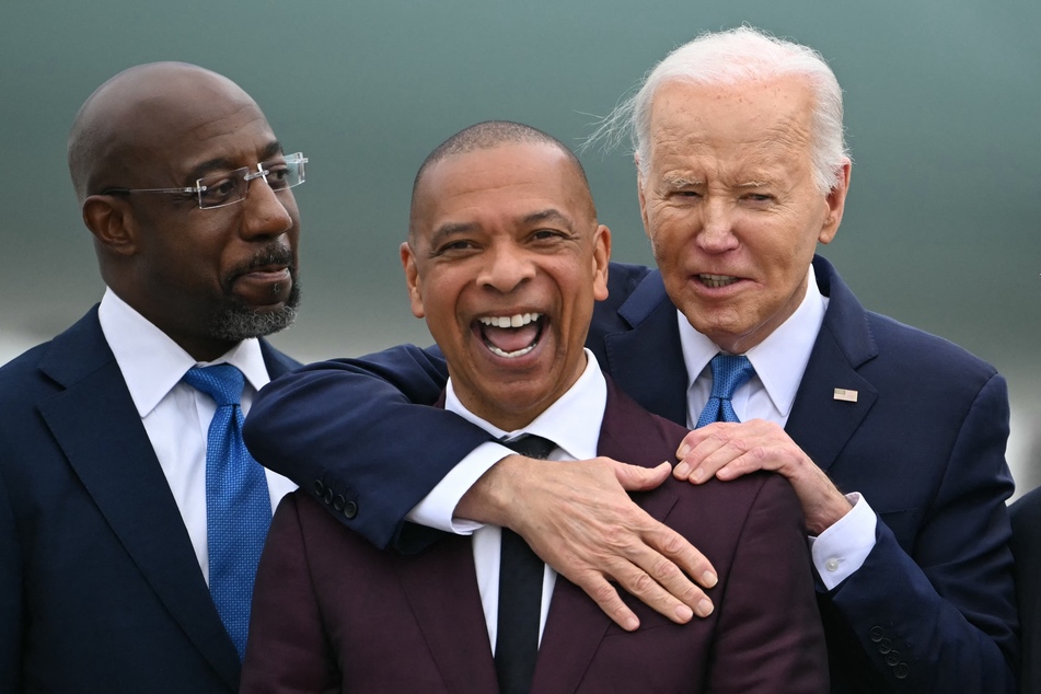 President Joe Biden (r.) embraces Marlon Kimpson (c.), member of the Advisory Committee for Trade Policy and Negotiations in the Office of the US Trade Representative, as Georgia Senator Raphael Warnock (l.) looks on upon Biden's arrival in Atlanta, Georgia on Saturday ahead of campaign events.