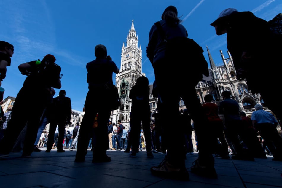 Touristen verfolgen das Glockenspiel auf dem Marienplatz in München. (Archivbild)