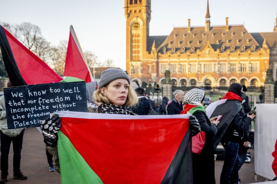 A protestor holds a Palestinian flag during a January 2024 demonstration held during a hearing at the International Court of Justice on a genocide complaint filed by South Africa against Israel.