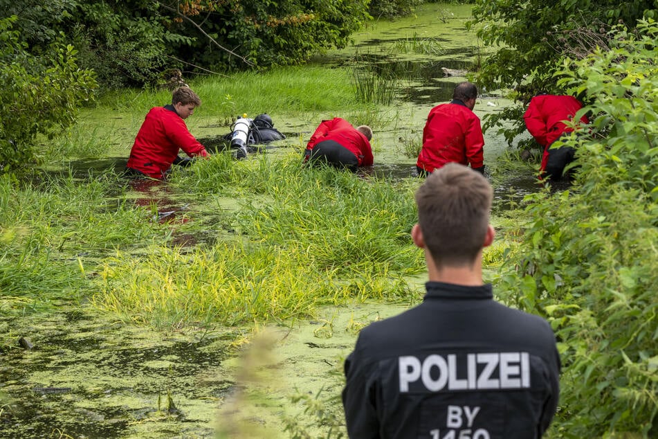 Taucher der Polizei suchen einen kleinen Weiher in der Gemeinde Taufkirchen nach der Vermissten aus Unterhaching ab.