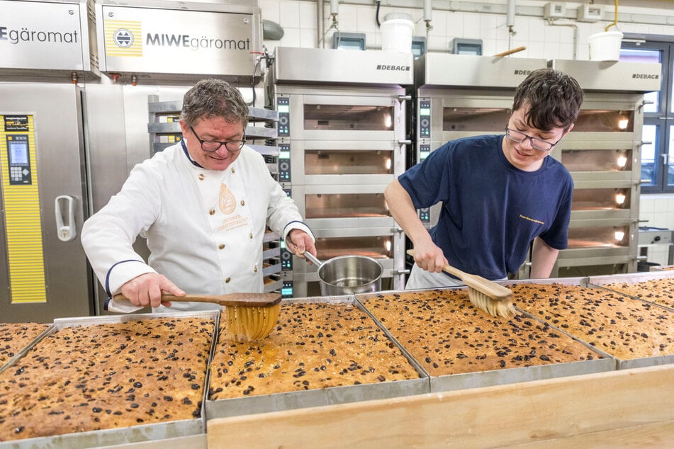 Bäckermeister Karsten Liebscher (52) und Sohn Alfred (18) beim Fetten der Stollenplatten.