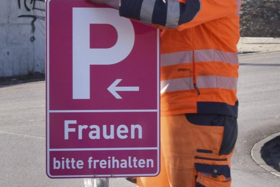 Ein Mitarbeiter der Stadt montiert an einem Parkplatz in Eichstätt ein pinkfarbenes Verkehrsschild.