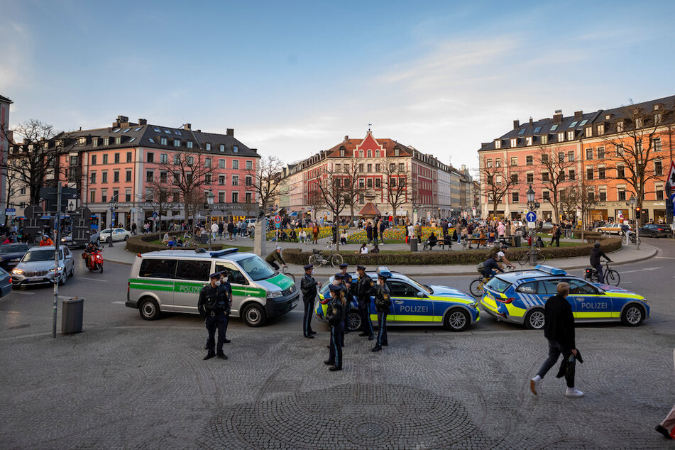 Polizisten stehen am Gärtnerplatz im Herzen der Stadt, während Passanten auf dem Platz verweilen.