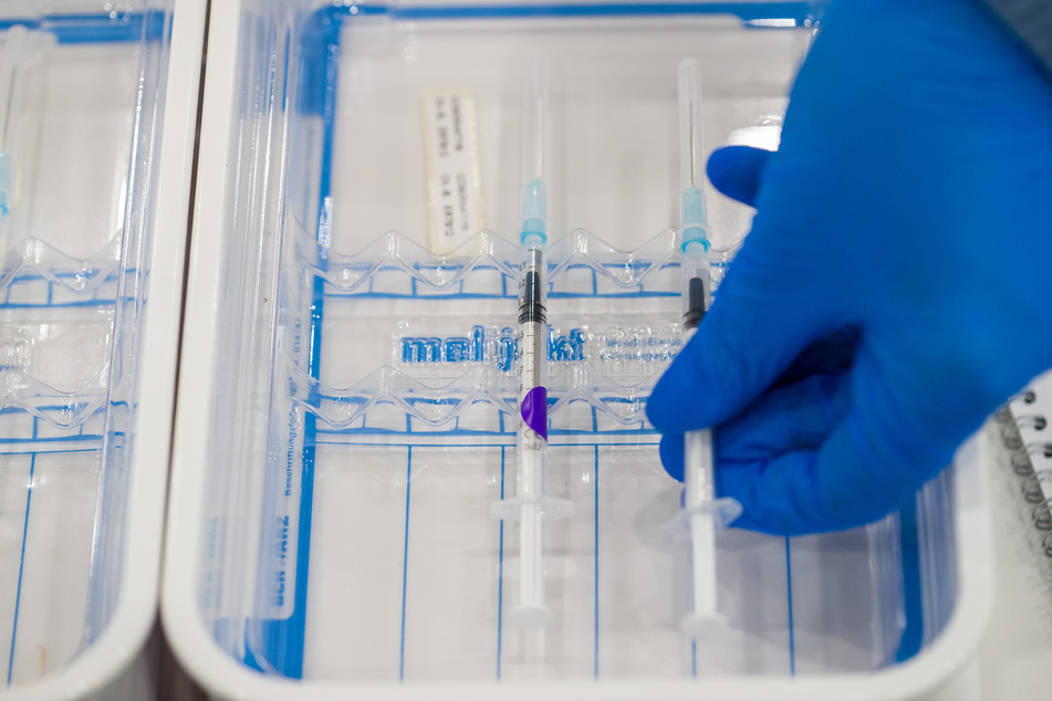 Eine medizinische Fachkraft legt im Nürnberger Impfzentrum auf dem Messegelände eine aufbereitete Impfspritze mit dem Pfizer-BioNTech-COVID-19-Impfstoff in eine Schale.