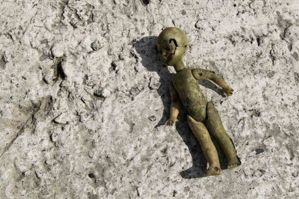 Eine kaputte Babypuppe liegt verlassen auf dem Boden (Symbolbild).
