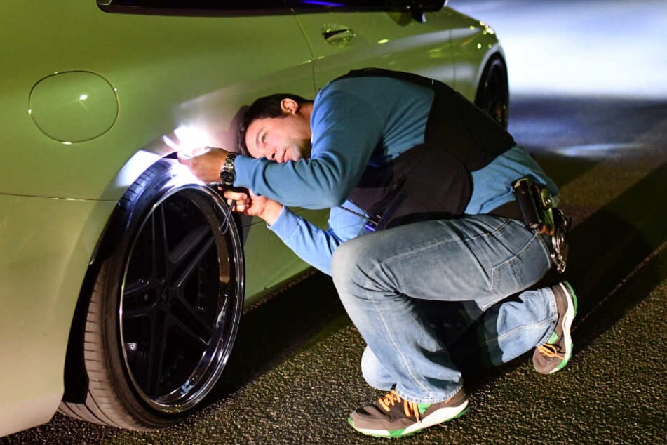 Ein Polizeibeamter nimmt ein getuntes Auto genauer unter die Lupe.