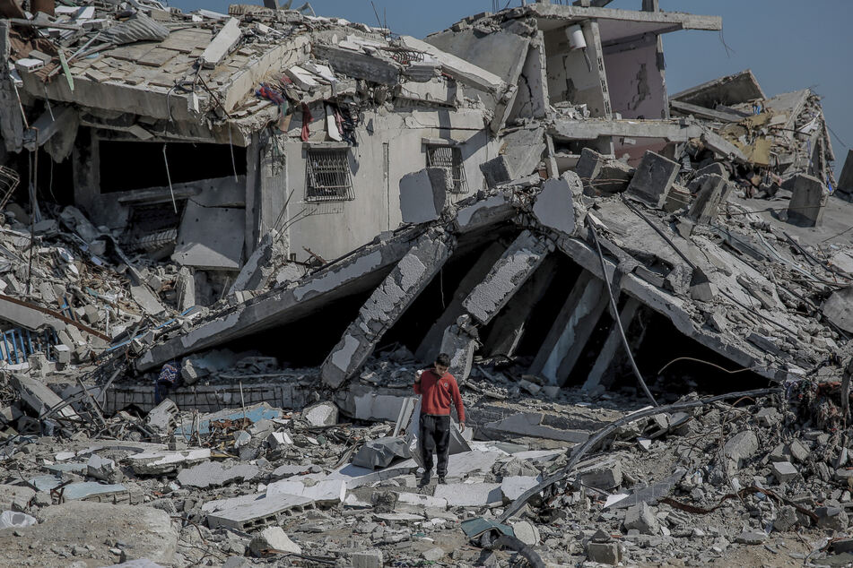 Ein palästinensischer Junge geht neben einem beschädigten Gebäude auf dem Weg zurück zu seinem Haus.