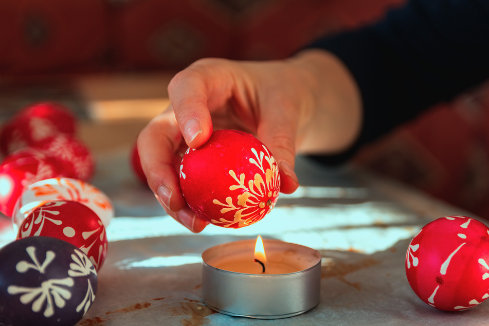 Halte das Ei seitlich an die Flamme und schwenke es leicht, um das Wachs zu entfernen.