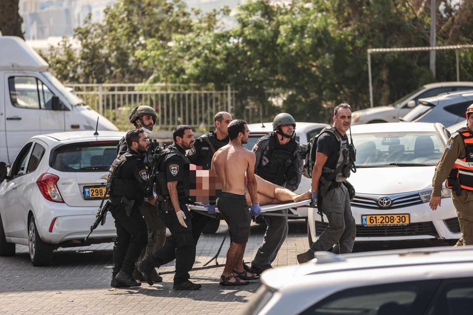Mitglieder der israelischen Sicherheitskräfte tragen in Ashkelon nach einem Raketenangriff aus dem Gazastreifen einen Verletzten auf einer Trage.