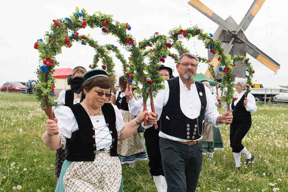 Traditionelle Trachten mit Blumentanzbögen vor einer Bockwindmühle: So ein Mühlenfest kann schonmal so richtig abgehen! (Symboldbild)