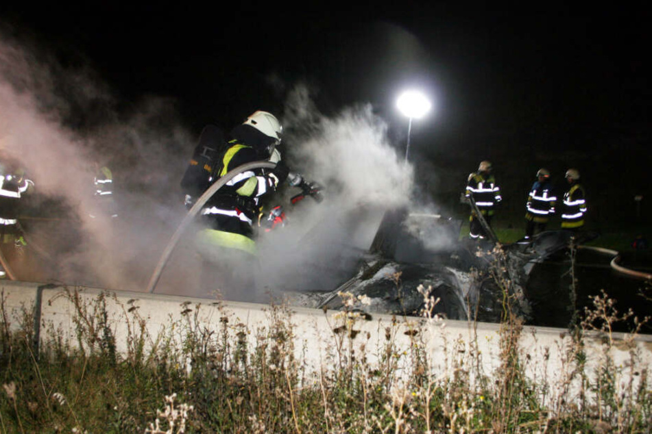 Die Feuerwehr löscht das brennende Auto.