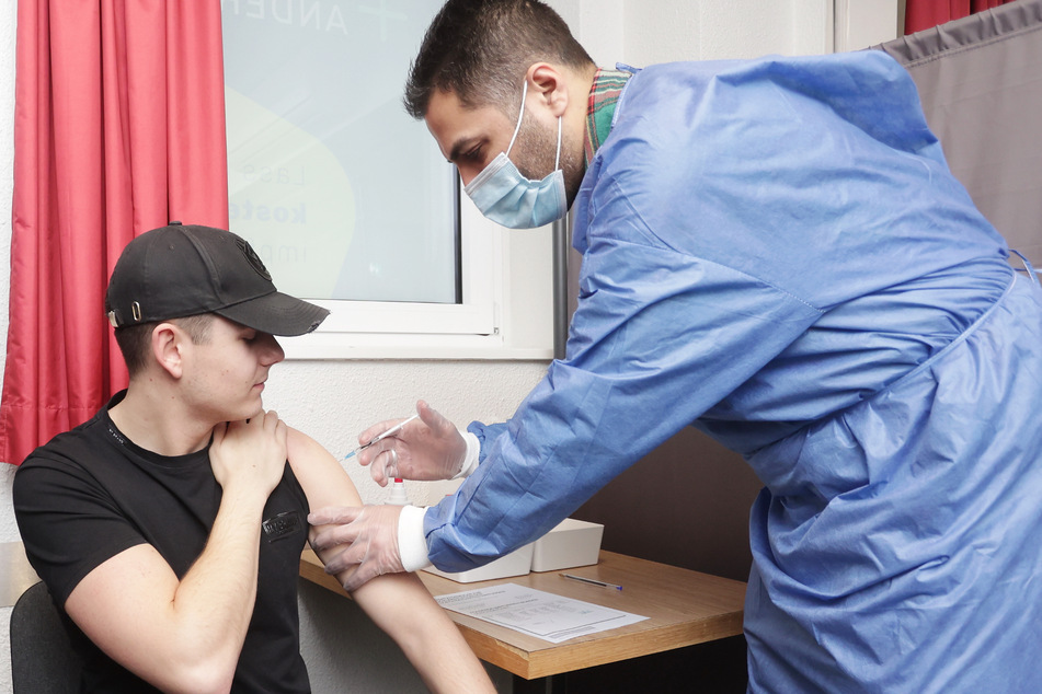 Luke van B. (23, l) wird bei einem Weihnachts-Impfmarathon in einem Hotel von Arzt Ahmad-Mujtaba Mostakiem mit dem Biontech-Impfstoff gegen Corona geimpft.