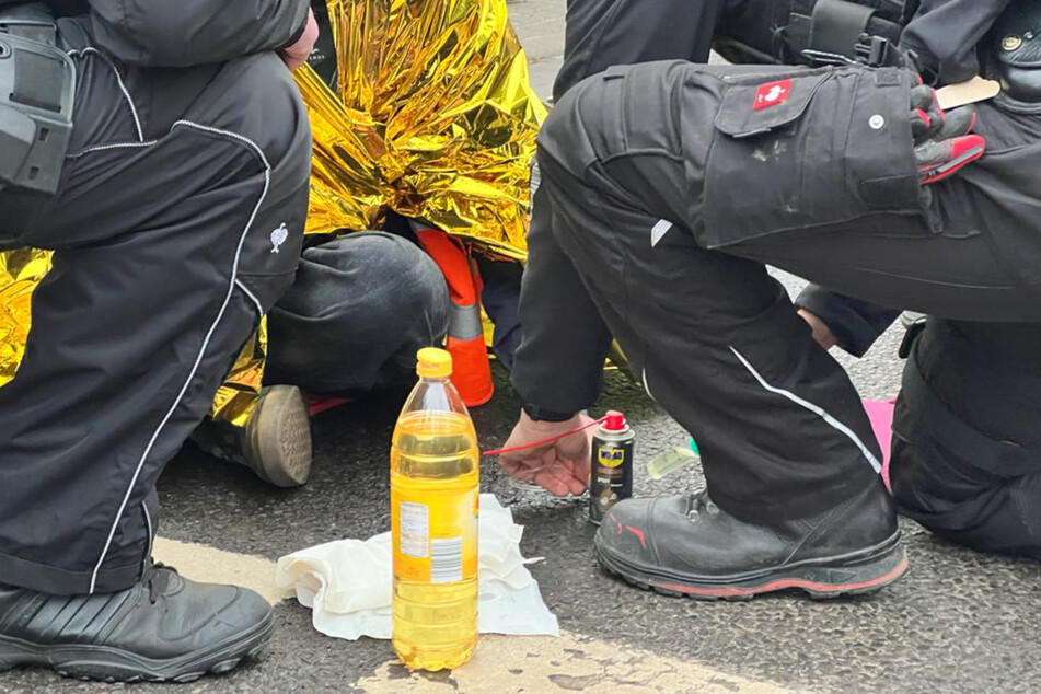 Mithilfe von Speiseöl werden die Aktivisten von der Straße gelöst.