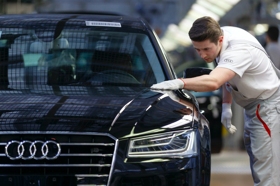 Ein Werksmitarbeiter kontrolliert in einer Produktionshalle von Audi an einem Bandende einen A8.