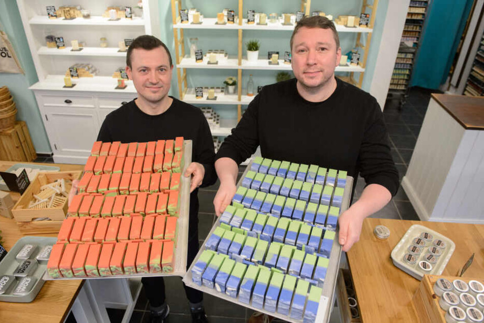 Cosmin Katko (l) und Marc-Simon- Wolf vom Seifenhersteller Housed Wolf GbR halten in ihrem Laden in Nürnberg Tabletts mit den Seifen von der Sorte Macintosh (l) und Kentish Green in den Händen.