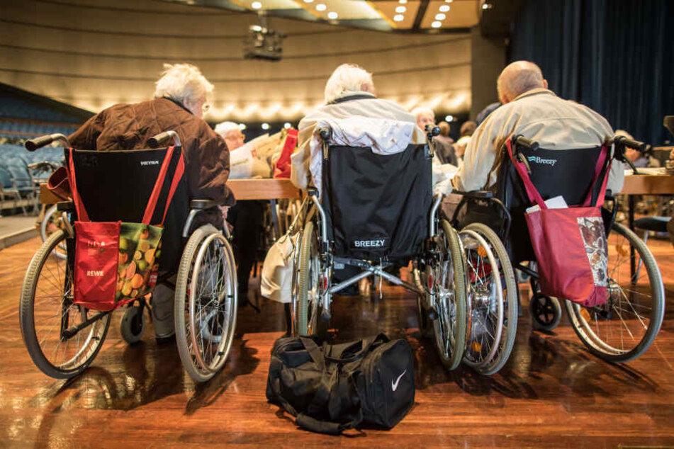 Drei ältere Menschen in Rollstühlen in einer Sammelstelle. Viele Menschen sind auf die Hilfe anderer bei der Evakuierung angewiesen.