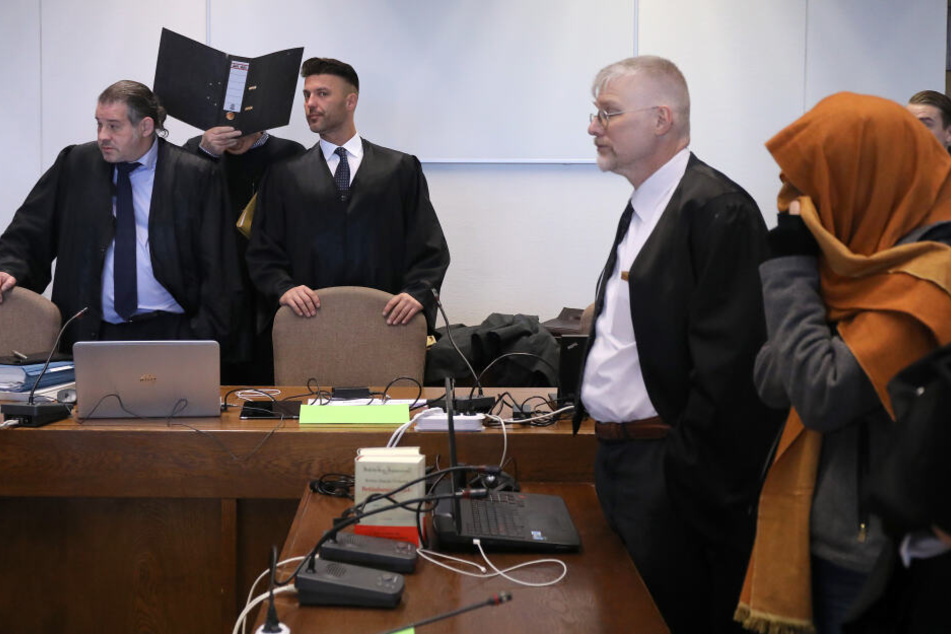 Zwei wegen bandenmäßigen Kokainschmuggels Angeklagte (2.v.l und r) stehen zwischen ihren Anwälten im Gerichtssaal des Landgerichts.
