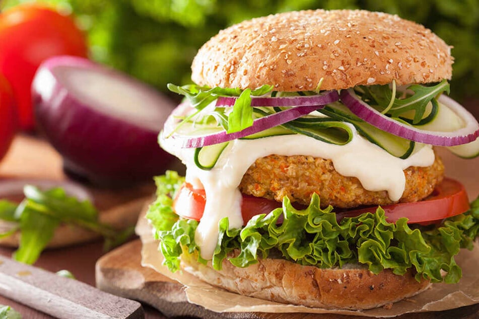 Vegetarischer Karotte-Hafer-Burger mit Gurke, Zwiebel und Tomate.