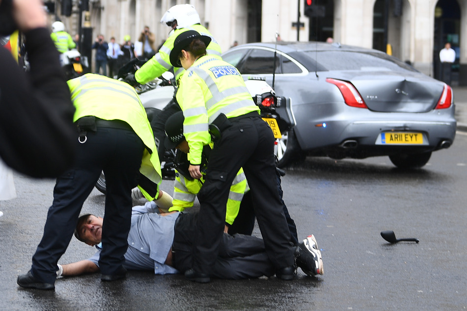 Polizeibeamte verhaften einen Mann, der zuvor vor das Auto des britischen Premierminister Johnson gelaufen ist.