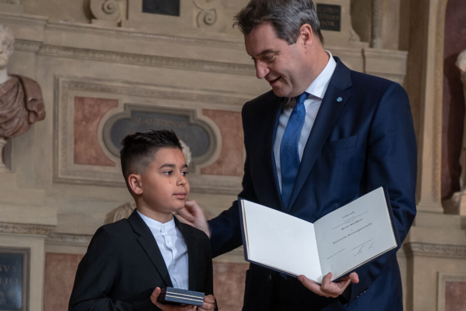 Kenan Büyükhan aus Nürnberg bekommt von Markus Söder (CSU), Ministerpräsident von Bayern, die Christophorus-Medaille überreicht.