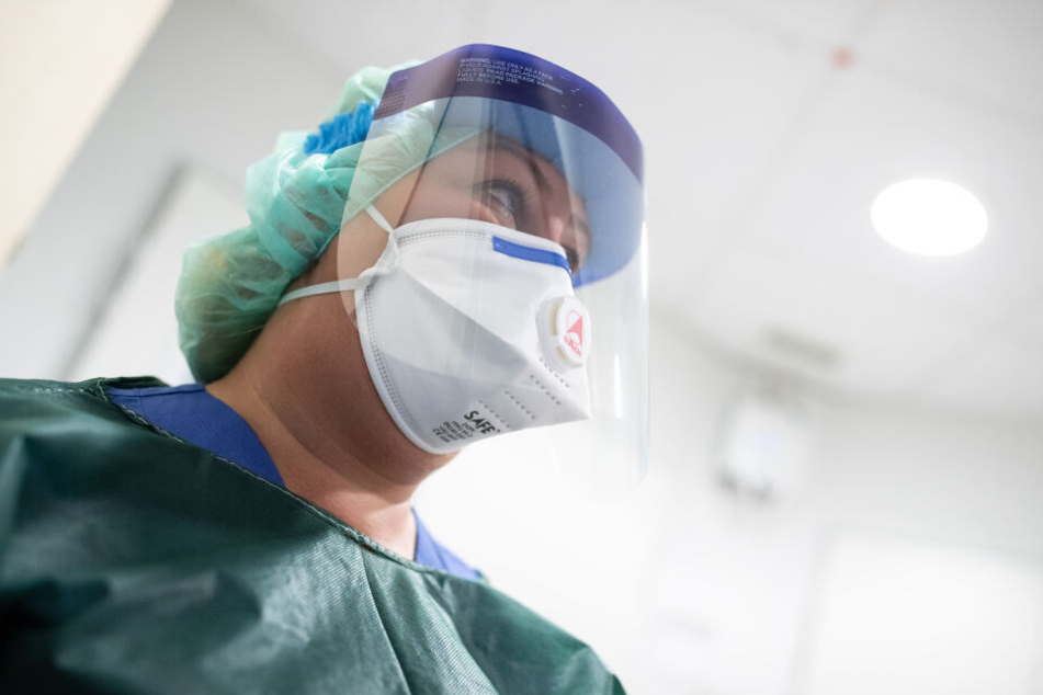 Canan Emcan, Stationsleiterin auf der Infektionsstation der Uniklinik Essen, steht in Schutzkleidung und mit einer Atemmaske in einer Schleuse.