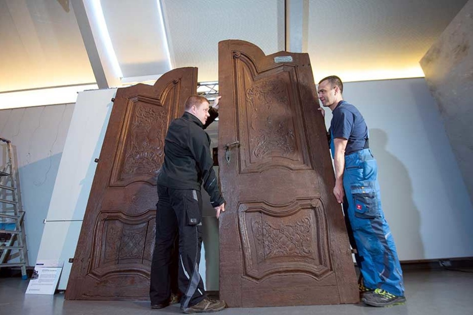René Lübeck (38, l.) und Sandro Frenzel (42) werkeln am größten Ausstellungsstück der Sonderausstellung 900 Jahre Zwickau: eine 2,60 Meter hohe Gaststättentür aus dem 18. Jahrhundert. Sie wurde beim Abriss der Zwickauer Altstadt gerettet.