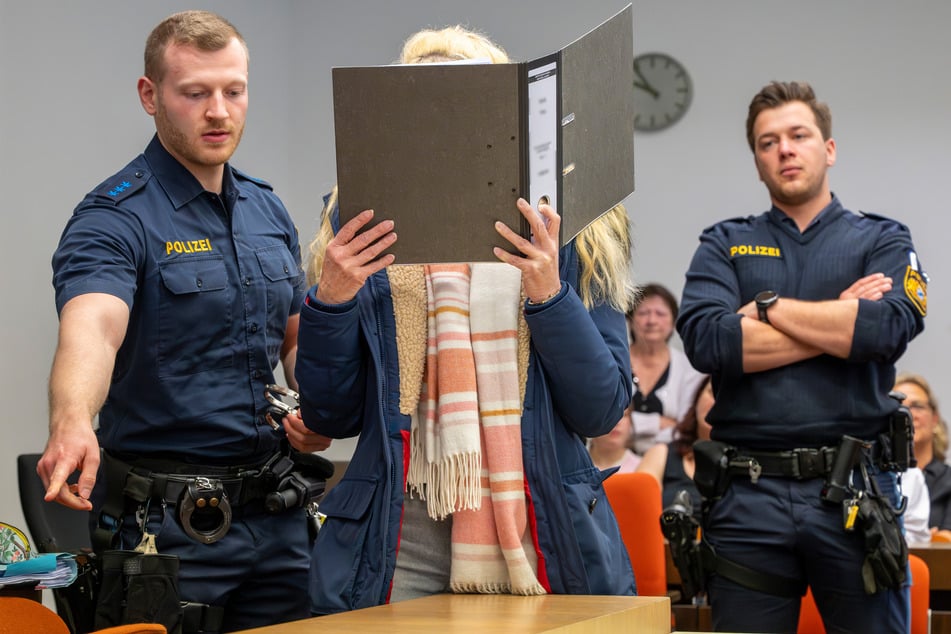Eine Angeklagte hält im Gerichtssaal des Landgericht II einen Aktenordner vor ihr Gericht.