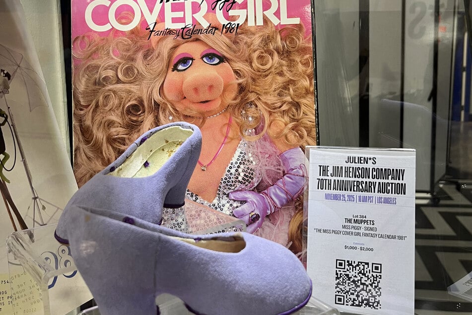 The Miss Piggy signed Cover Girl fantasy calendar 1981 is on display with a pair of her production-worn shoes for the Couldn't We Ride bicycle scene of The Great Muppet Caper during a preview of the Jim Henson Company 70th Anniversary Auction at Julien's Auctions warehouse in Gardena, California, on November 19, 2025.