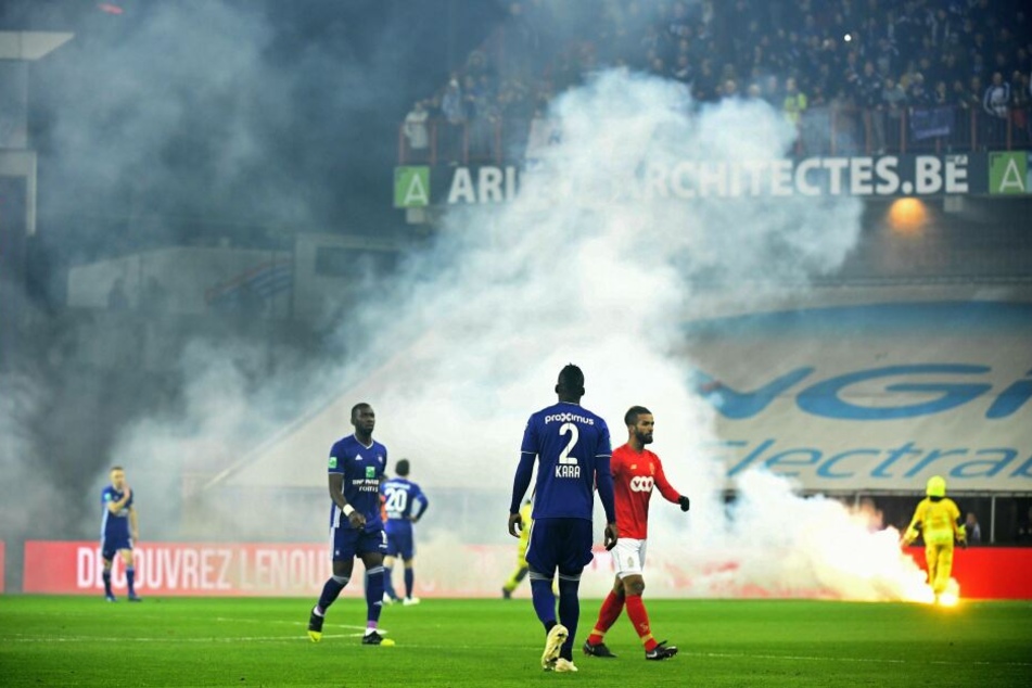 Die Spieler beider Mannschaften verlassen aufgrund der Raketen, die aufs Spielfeld fliegen, den Rasen.