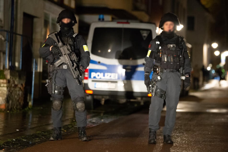 Einsatzkräfte stehen mit Maschinengewehren in einer Straße.