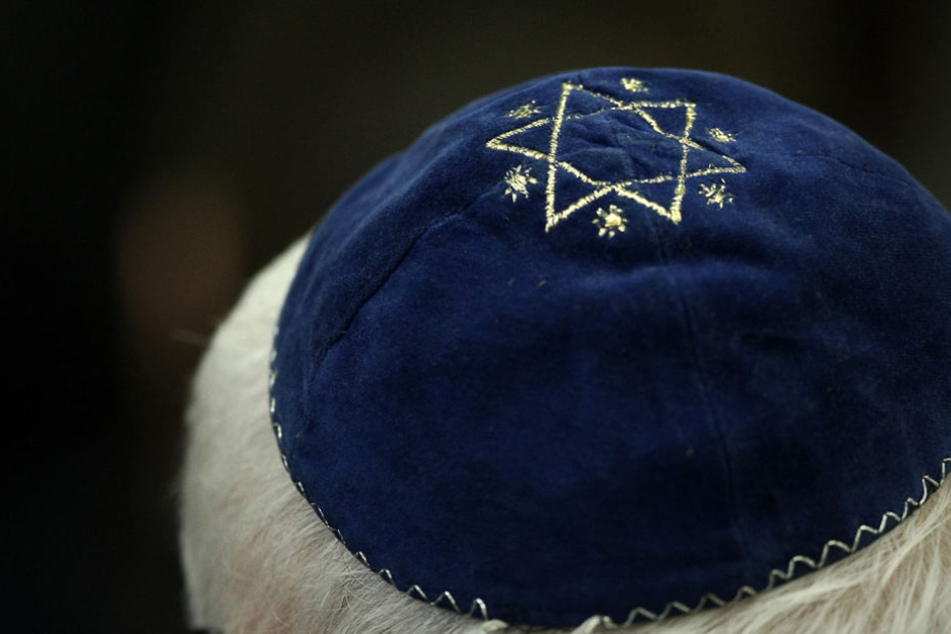 Ein Mann trägt in einer Synagoge eine Kippa mit einem aufgenähtem Stern.