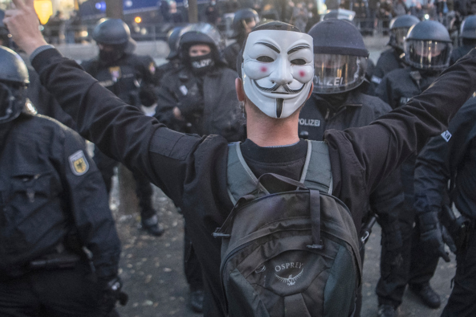 Ein Teilnehmer der Querdenken-Demonstration unter dem Motto "Kein Lockdown für Bembeltown!" stellt sich in Frankfurt mit ausgebreiteten Armen vor Polizisten.
