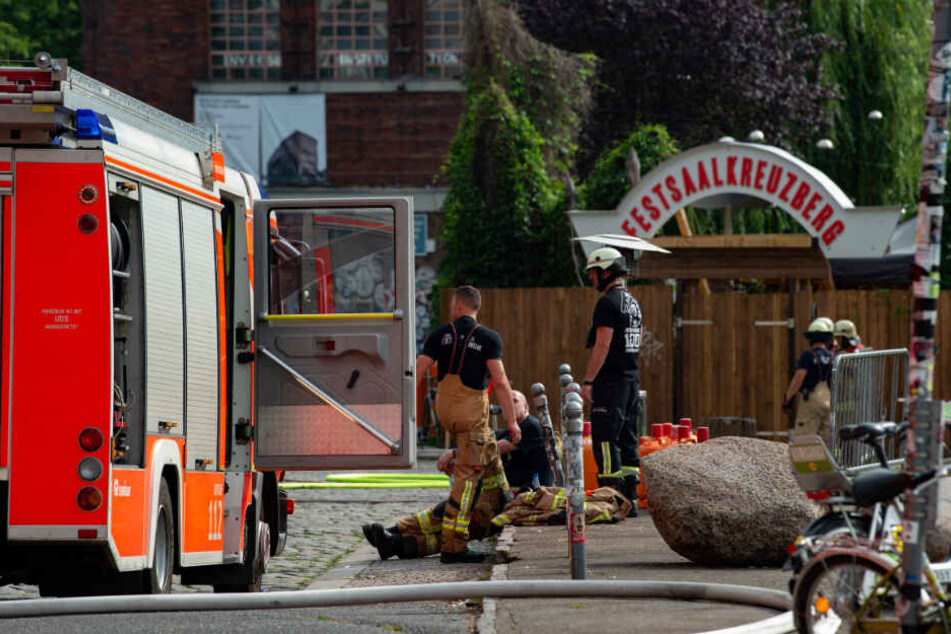 Feuerwehrleute stehen an der Straße "Am Flutgraben" in Kreuzberg.