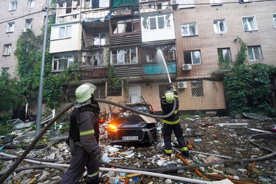 Feuerwehrleute bekämpfen nach dem russischen Angriff auf ein Wohnhaus in Charkiw einen Brand.