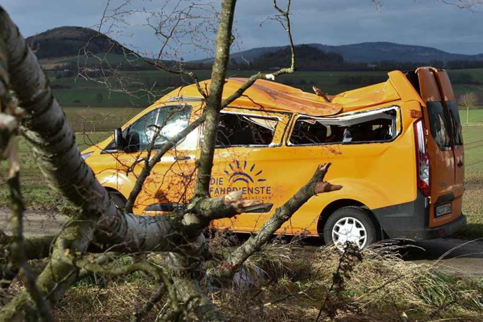 Ein Schul-Minibus steht in Deute (Hessen) zerstört am Straßenrand, nachdem er zuvor von einem im Sturm umstürzenden Baum getroffen wurde.