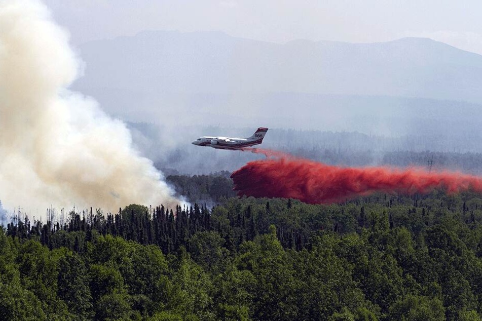 Ein Conair AVRO RJ85 AT-Löschflugzeug lässt Löschmittel über einem Waldbrand ab.