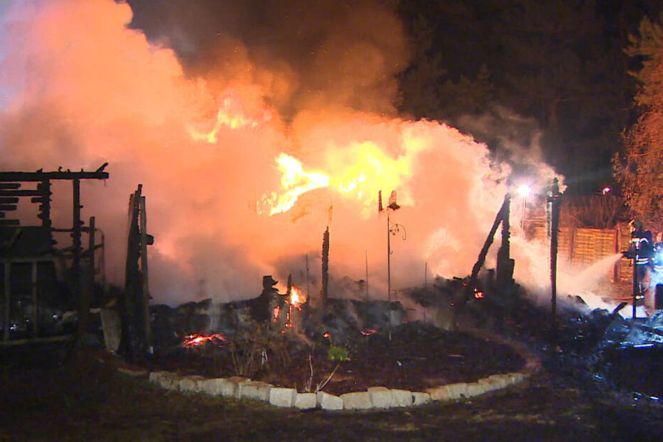 Feuerwehrleute löschen die Flammen, die aus den Überresten eines Einfamilienhauses schlagen.
