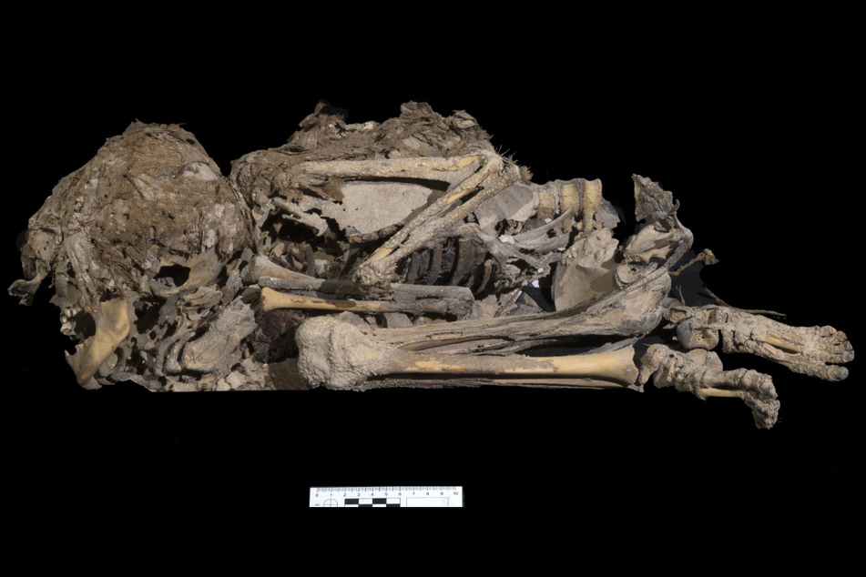 Ein 6000 Jahre altes Skelett eines Mädchens oder eines Jungen, das in Stoff eingewickelt begraben worden war und bei Ausgrabungen in einer Höhle in der Nähe des Toten Meeres entdeckt wurde. Neben dem Skelett sind nun verschiedene Gegenstände sowie Fragmente einer Bibel-Schriftrolle entdeckt worden.