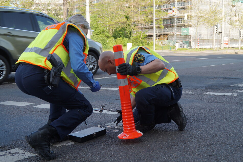 Polizisten entfernten den angeklebten und im Asphalt verschraubten Poller.