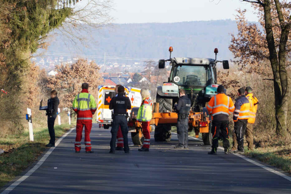 Einsatzkräfte stehen vor dem Traktor.