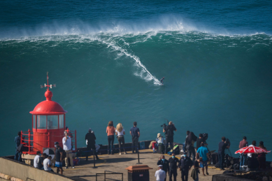 Mega-Spektakel auch für das Publikum: Gäste sehen dem Big-Wave-Surfer Sebastian Steudtner (36) aus Deutschland zu, während er am Praia do Norte ("Nordstrand") einer gigantischen Welle reitet. Im portugiesischen Nazaré entstehen die weltweit größten Wellen.