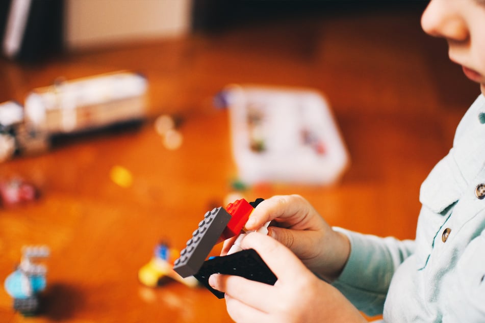 A child plays with various Lego bricks.