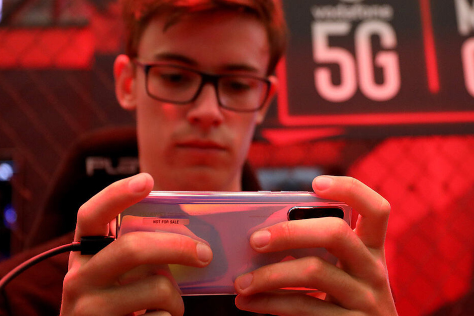 Ein Mitarbeiter von Vodafone spielt auf der Gamescom ein Computerspiel auf einem Smartphone über das 5G Mobilfunknetz.