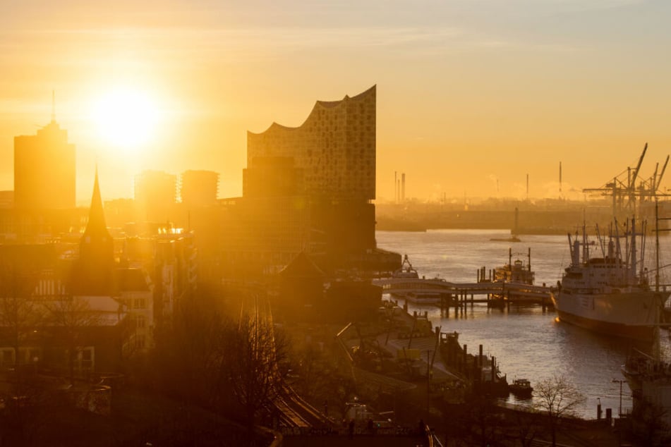 Die Sonne geht über der Elbphilharmobie und dem Hamburger Hafen auf.